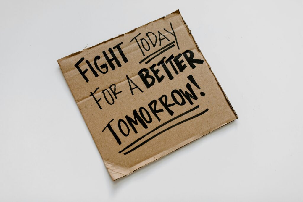 Cardboard sign with 'Fight today for a better tomorrow!' message on a white background.